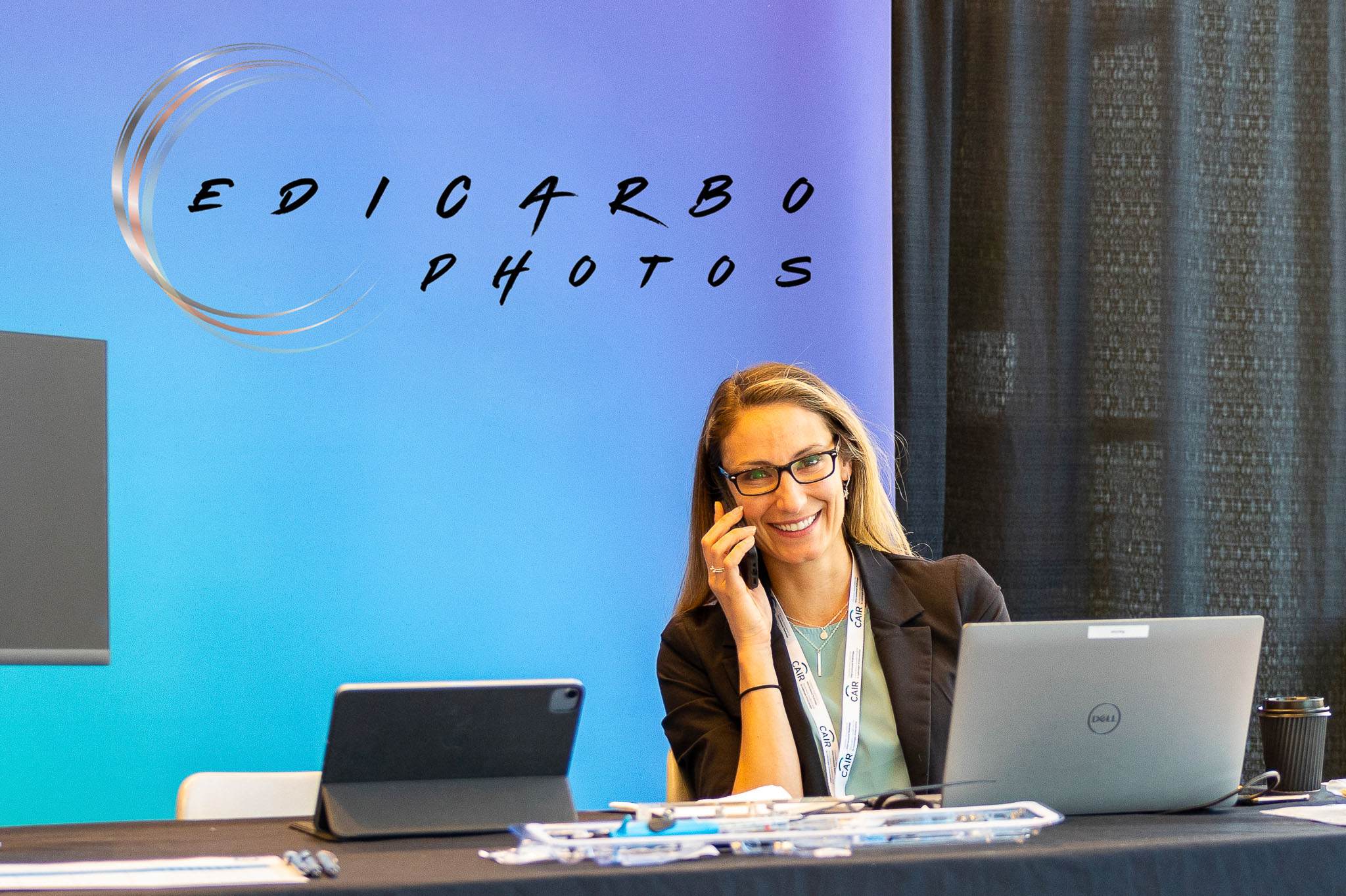 photo d'une personne d'affaire au téléphone devant son écran d'ordinateur, tout sourire, qui communique avec edicarbo photographe