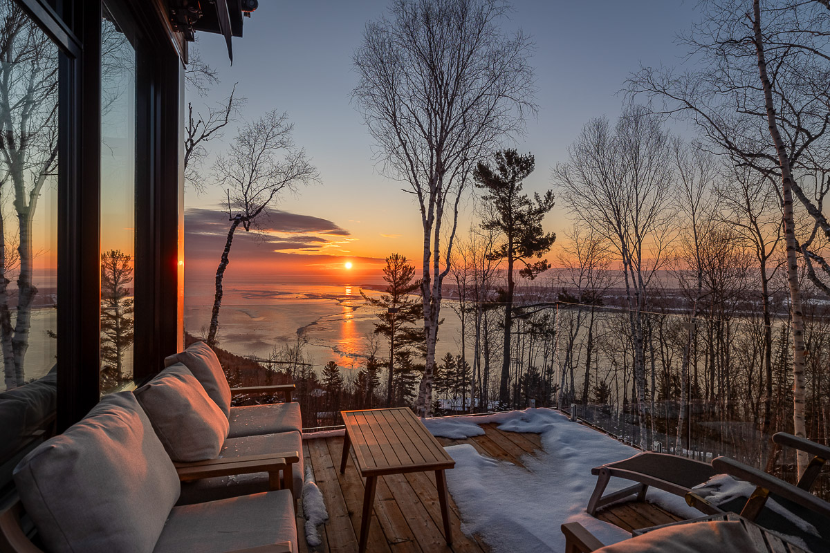 Chalet locatif dans Charlevoix avec vue du lever de soleil en hiver avec reflets sur le fleuve Saint-Laurent glacé